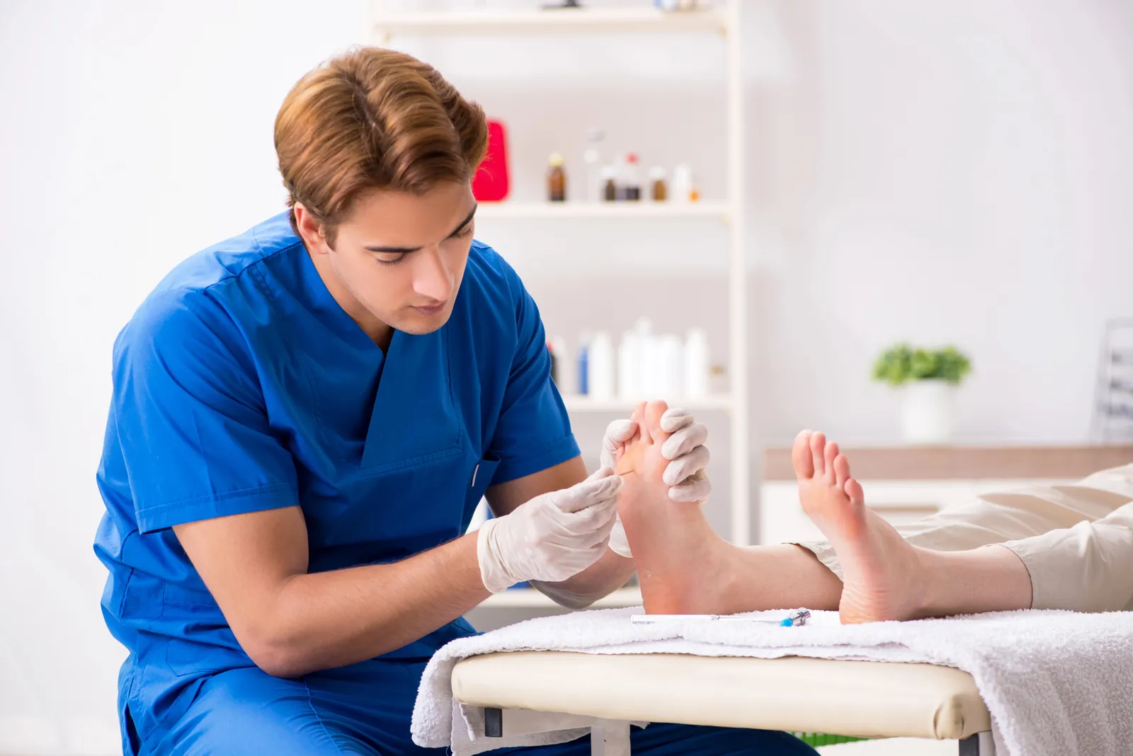 Profesional sanitario con guantes explorando con las manos el antepié de un paciente