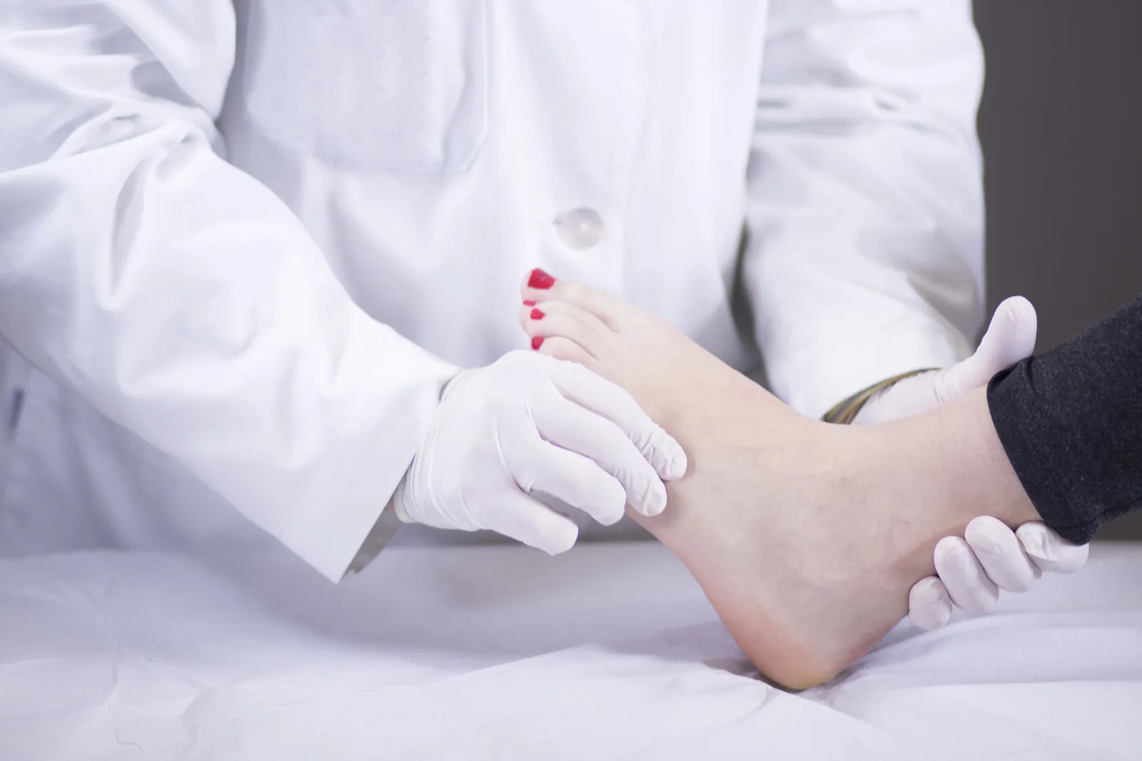 Profesional sanitario con guantes explorando el pie de un paciente